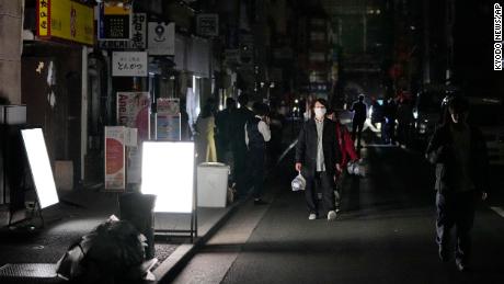 Pessoas andam por uma rua durante uma queda de energia em Tóquio.