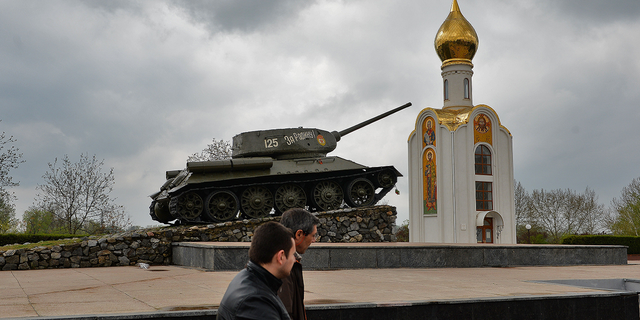Pessoas passam por um tanque da era soviética, agora um monumento que celebra a vitória do Exército Vermelho contra a Alemanha fascista, em Tiraspol, a principal cidade da Transnístria, Moldávia, em abril de 2014.