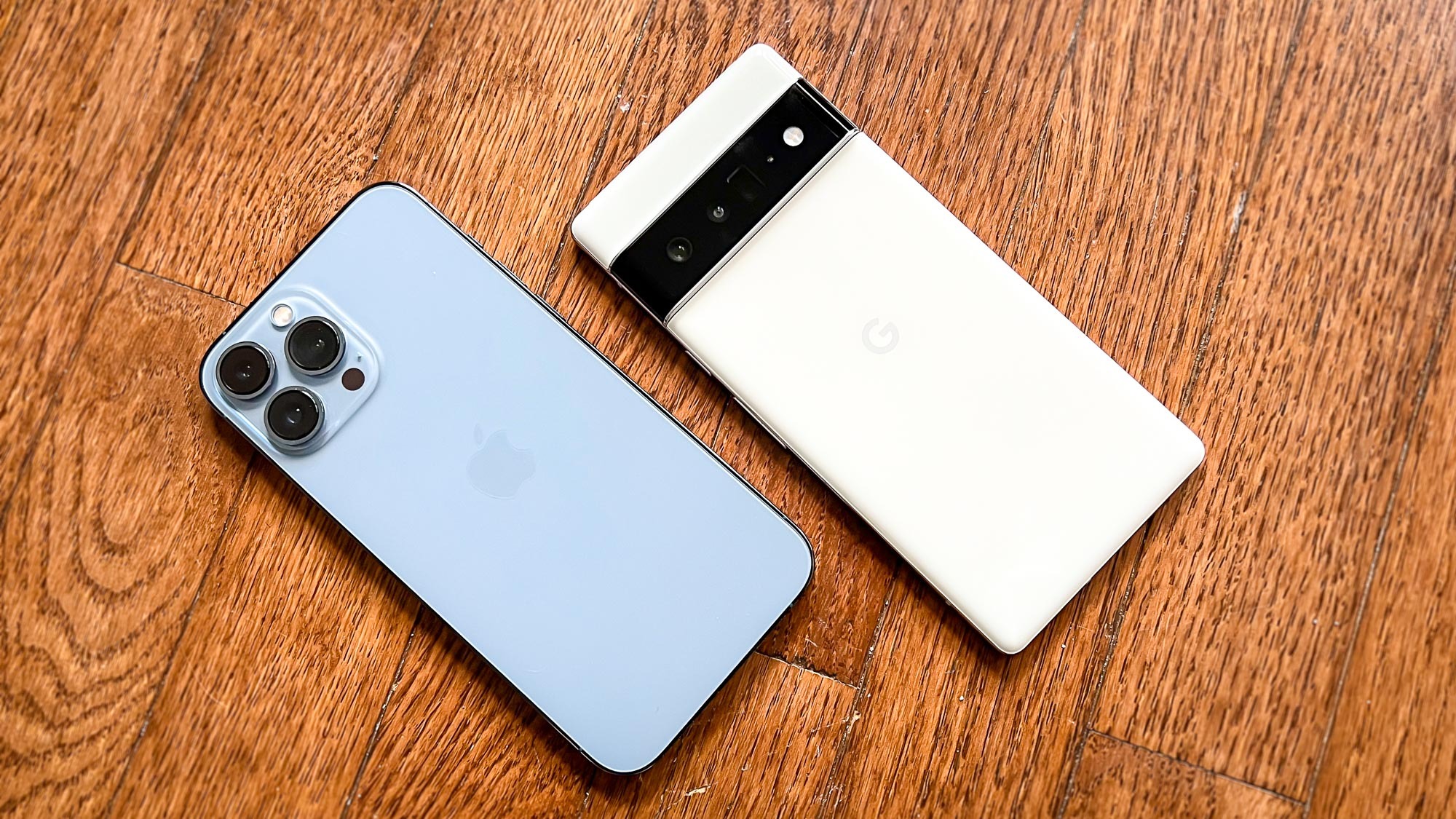 pixel 6 pro vs iphone 13 pro max: ambos os telefones ficam virados para baixo em um piso de madeira