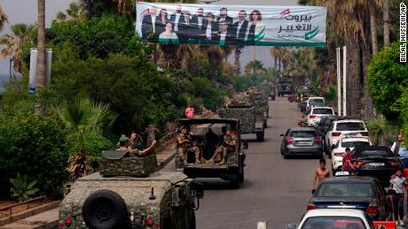 Veículos do exército libanês passam por um outdoor representando candidatos para as eleições do Parlamento no domingo em Beirute, Líbano, em 14 de maio.