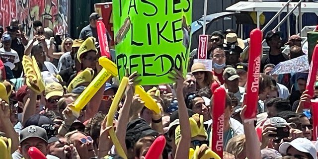 Uma pessoa segurando uma placa que diz "Tem gosto de liberdade" Durante o famoso concurso de cachorro-quente de Nathan em Coney Island em 4 de julho de 2022.