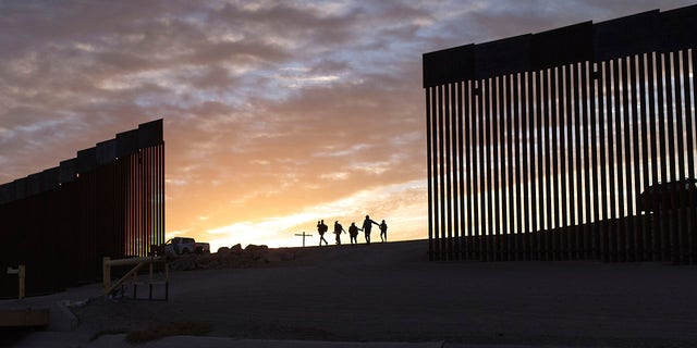 ARQUIVO - Famílias de imigrantes do Brasil passam por uma brecha no muro da fronteira para chegar aos Estados Unidos após cruzarem do México para Yuma, no Arizona, em busca de asilo.