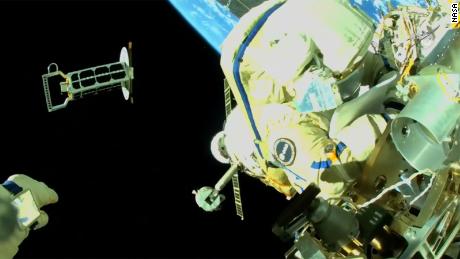 Cristoforetti pode ser visto trabalhando no exterior da Estação Espacial Internacional enquanto Artemyev, cuja mão é mostrada no canto inferior esquerdo, lança um nano-satélite em órbita. 