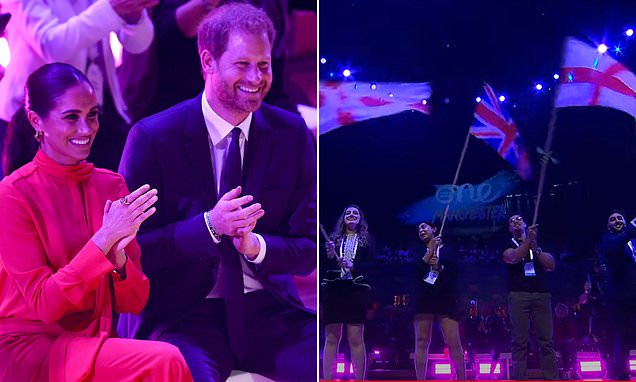 O duque e a duquesa de Sussex aplaudem entusiasticamente enquanto a bandeira britânica tremula no topo do One Young World
