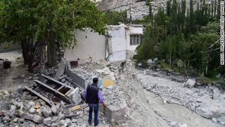Um morador local fica ao lado de sua casa destruída em junho, depois que uma explosão de um lago glacial causou inundações catastróficas na vila de Hassanabad, no norte do Paquistão. 