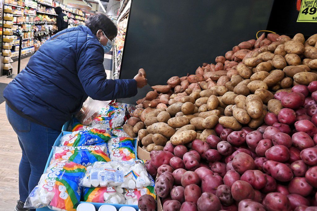 Uma mulher distribui batatas em uma mercearia.